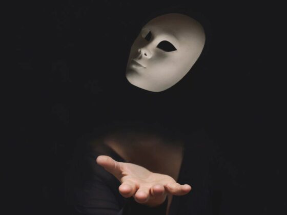 hand of a person hidden in the dark throwing a mask in the air